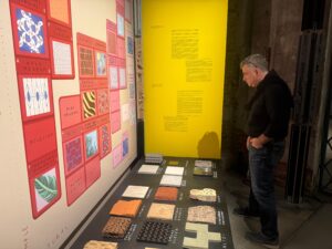 Prof. Novoselov studies natural and synthetic material samples displayed in the curated Material Bank wall, reflecting interdisciplinary innovation.